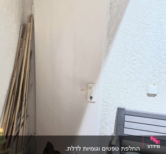 דלת כניסה לבנה עם ציפוי קלוף ופגום בחלקה התחתון